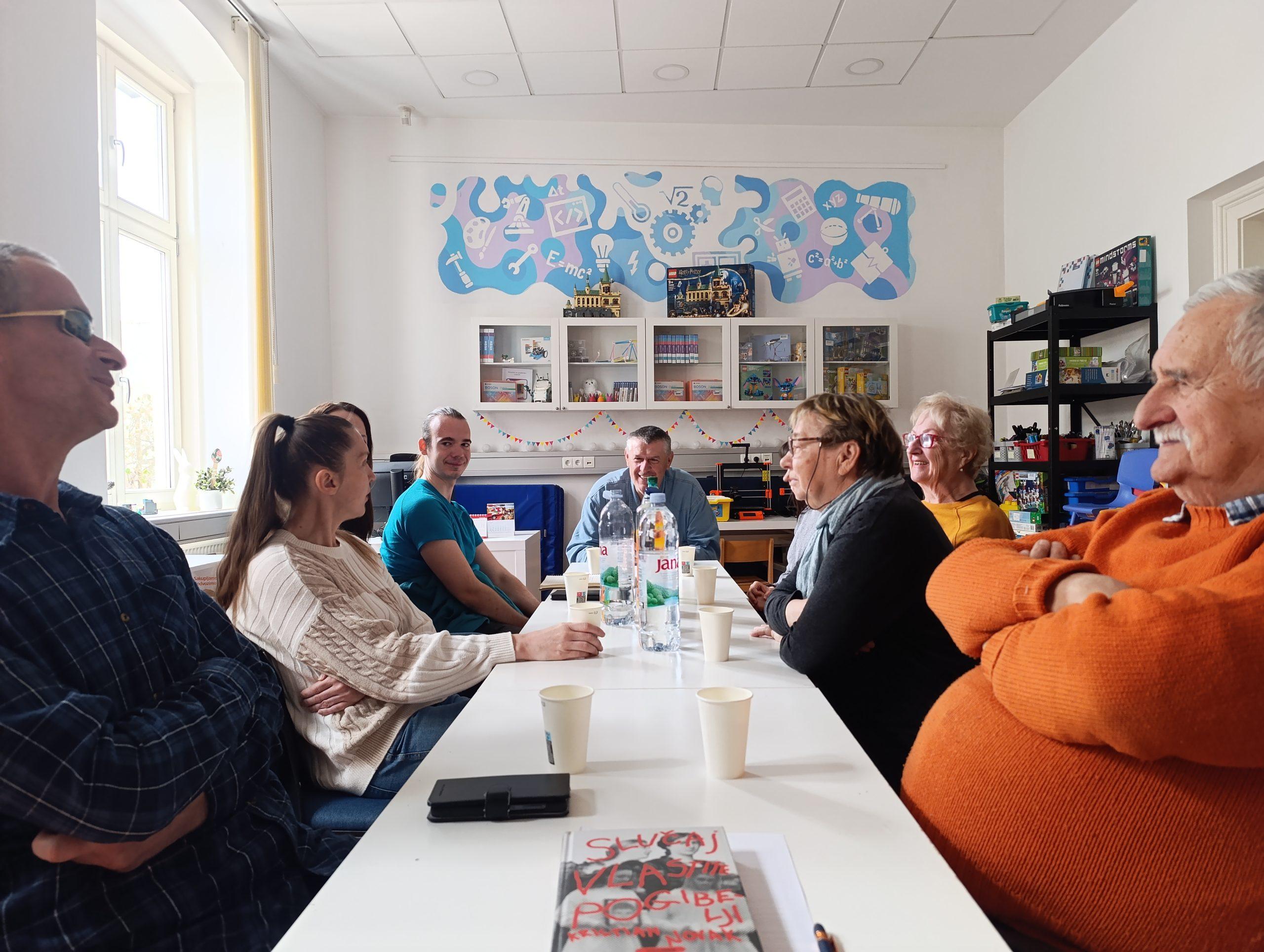 članovi sjede oko stola i razgovaraju o knjizi Slučaj vlastite pogibelji od Kristiana Novaka